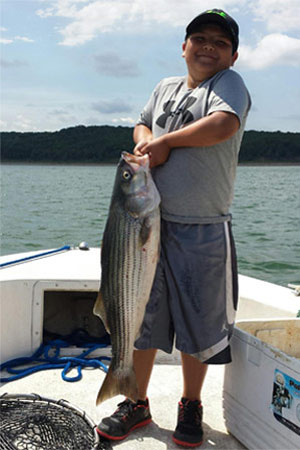 Kid holding striped bass at Lake Texoma after trip with Randy Wylie's Guide Services