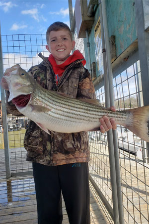 Kid holding striped bass at Lake Texoma after trip with with Wylie Guide Services