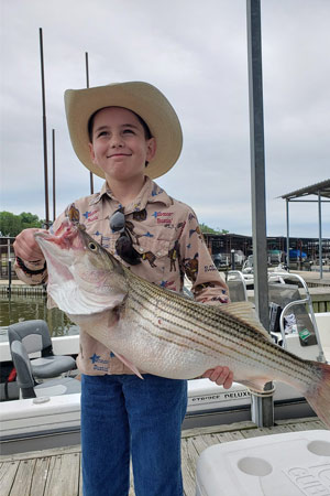 Kid holding striper at Lake Texoma after trip with Randy Wylie's Guide Services