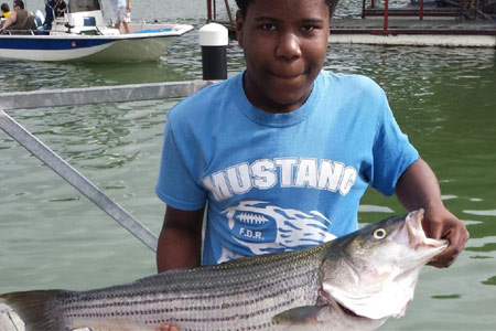 Kid holding striper at Lake Texoma after trip with Wylie Guide Services