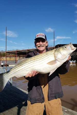 Man holding striper at Lake Texoma after trip with with Randy's Guide Service