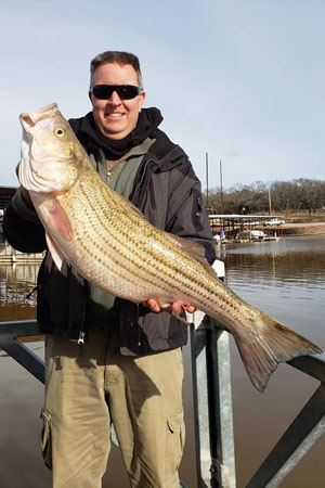 Man holding striper at Lake Texoma after trip with with Wylie Guide Services